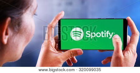 Poznan, Pol - Jul 10, 2019: Woman Holding Smartphone Displaying Logo Of Spotify, A Swedish Audio Str