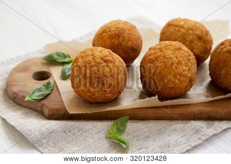 Homemade Fried Arancini With Basil On A White Wooden Background, Side View. Italian Rice Balls. Clos