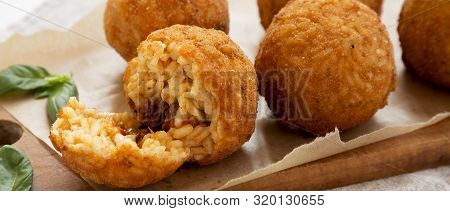 Homemade Fried Arancini With Basil On A Rustic Wooden Board, Side View. Italian Rice Balls. Closeup.