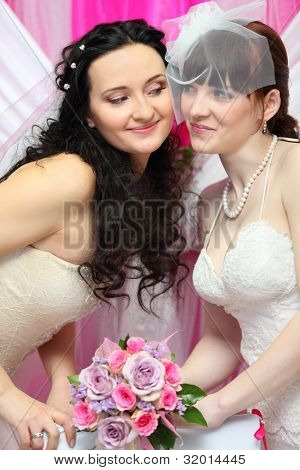 to glade brude ser på hinanden og holde smukke buket roser; Fokus på kvinder på venstre