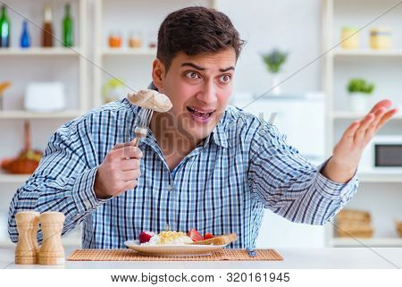 Man eating tasteless food at home for lunch