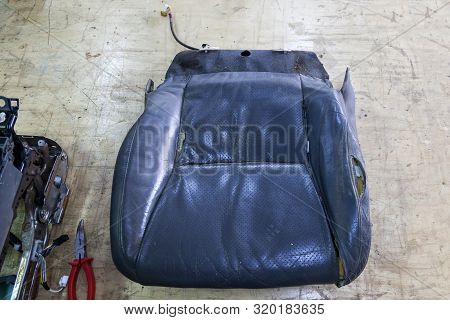 An Old Car Seat Made From Tattered And Torn Leather Upholstery On A Workbench In A Workshop For The 