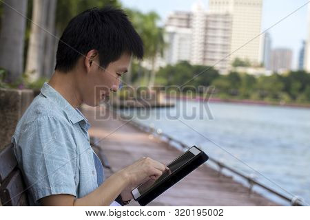 Young Asian  Using Figital Taplet With Her Business Online Shopping In A Garden Park , Online Shoppi