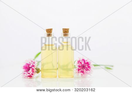 Essence Of Lavender Flowers On White Background In Beautiful Glass Bottle