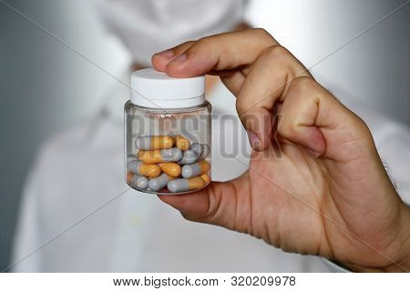 Doctor Giving Pills, Physician In Medical Mask Holding In Hand Bottle With Capsules. Concept Of Dose