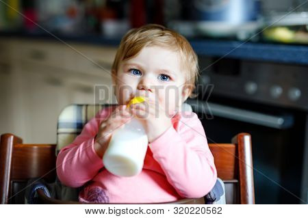 Cute Adorable Baby Girl Holding Nursing Bottle And Drinking Formula Milk. First Food For Babies. New