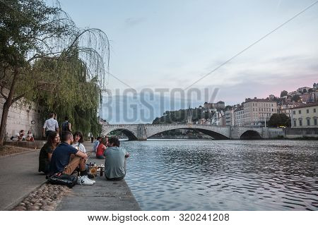 Lyon, France - July 17, 2019: French People, Mainly Young Men And Women Sitting On The Riverbank Of 