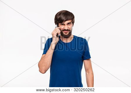 Displeased Handsome Brunet Man In A Blue Shirt With Beard And Mostaches Speaking On The Smartphone S
