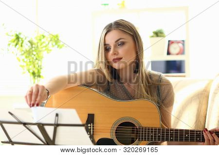 Woman Practice Acoustic Guitar Playing At Home. Female Player Performing While Sitting On Couch In L
