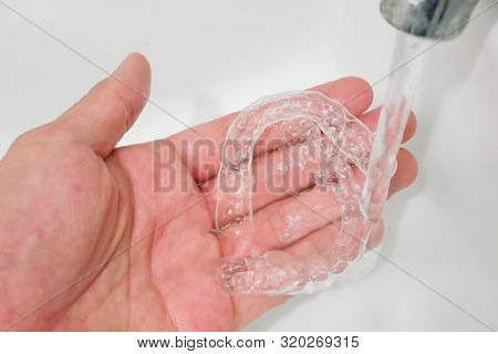 Hand Holding Clear Plastic Retainer Teeth That Isolated On Blue Sky Background. It's An Equipment Fo