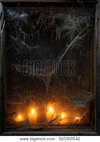 Spooky Halloween background. Scary card with old cobweb and burning candles in the dark