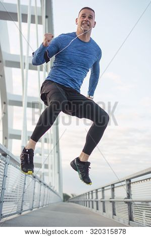 Sportsman Celebrating Successful Training With High Jump And Raised Hand. Low Angle View- A Man In T