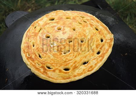 Pita Bread Baking On A Saj Or Tava On Fire, Close-up. Traditional Arabic Pita Bread