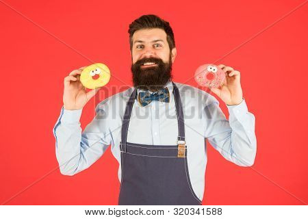 Baked Donuts With Funny Faces. Happy Baker Holding Home Baked Snack On Red Background. Hipster Smili