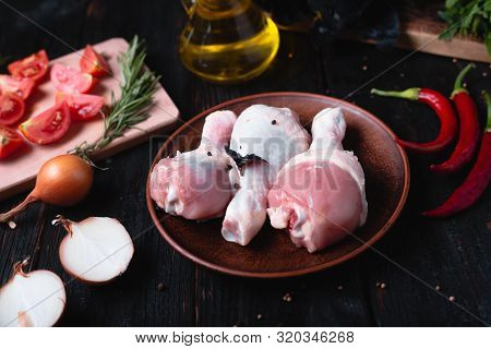 Raw Chicken Legs Lie On A Plate, Delicious Aromatic Spices, Hot Peppers And Garlic