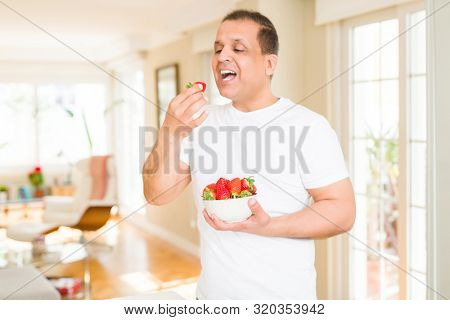 Middle age man eating straweberry at home