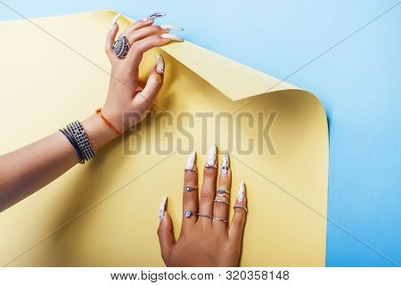 Woman Hands Holding Colorful Paper Copyspace Wearing A Lot Of Jewelry And Long Nails Closeup