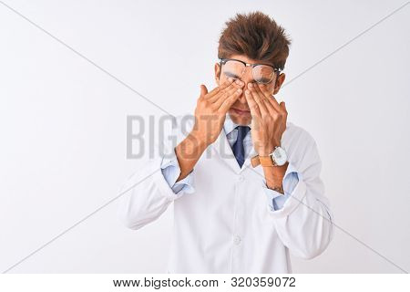 Young handsome sciencist man wearing glasses and coat over isolated white background rubbing eyes for fatigue and headache, sleepy and tired expression. Vision problem