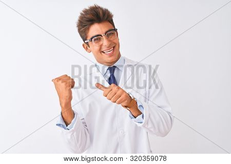 Young handsome sciencist man wearing glasses and coat over isolated white background Pointing to the back behind with hand and thumbs up, smiling confident