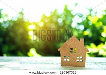 Closed Up Tiny Home Model On Floor Or Wood Board With Sunlight Green Bokeh Background. House Propert