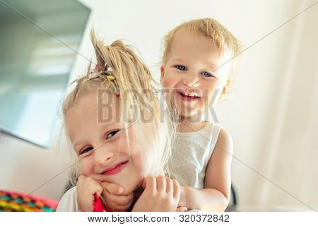 Cute Adorable Blond Caucaian Little Sister Hugging Her Toddler Brother.couple Of Cheerful Sibling Pl