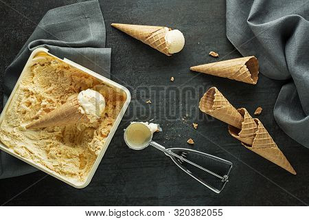 Vanilla Ice Cream Scoops, Scooped From Container In To Waffle Cones With A Silver Utensil