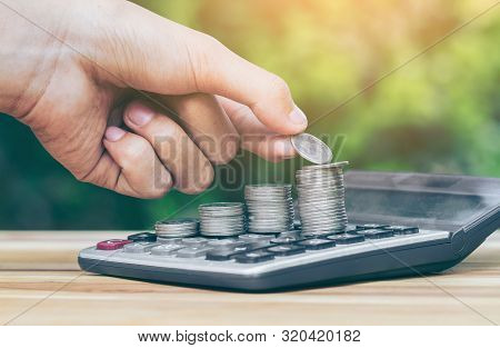 Coin Is Placed Is On The Calculator. Man Is Placing Is Coin. Planning Savings Money Of Coins To Buy 