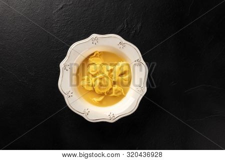 Italian Tortellini Served With Broth, Shot From The Top On A Black Background With Copy Space