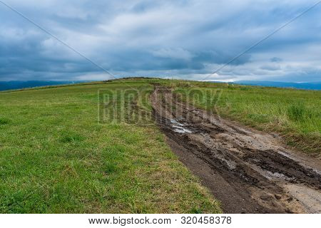 Dirt Road After Heavy Rain Leading To The Top Of The Hill, Stormclouds On The Dark Sky.