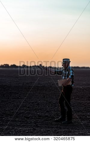 Profile Of Self-employed Man In Straw Hat Standing And Sowing Seeds