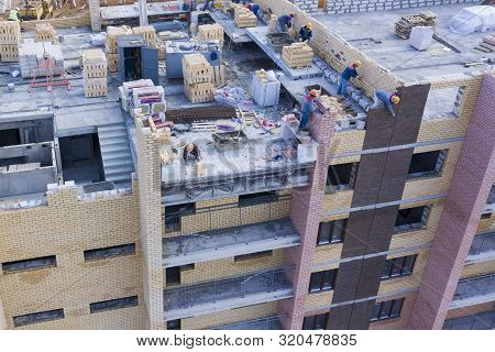 Construction Of A Multi-storey Building. Workers Lay Out A Wall Of Brick. The View From The Top.
