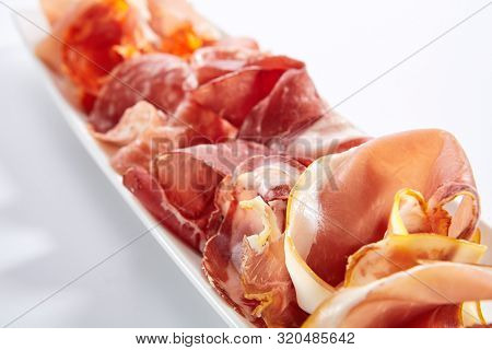 Meat assorti platter clopseup. Bresaola, coppa, speck and prosciutto slices. Beef and pork, chopped on plate. Served delicious snacks. Appetizer composition isolated on white background