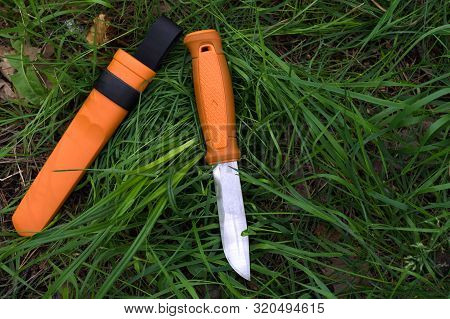 Hunting Knife In The Grass. Tourist Knife In The Grass. Knife With An Orange Handle.