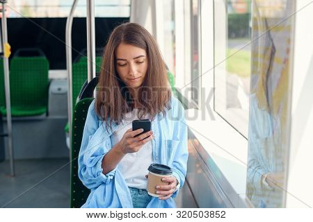 Pretty Female Passenger Sits With Smartp Hone While Moving In The Modern Tram Or Subway. Trip At The