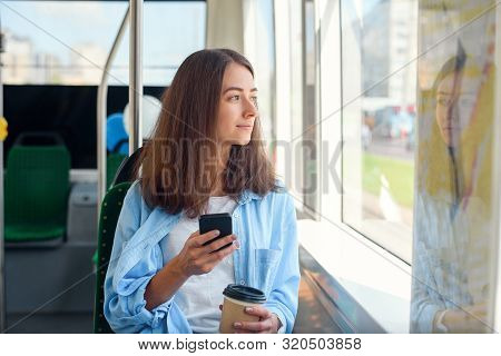 Pretty Female Passenger Sits With Smartp Hone While Moving In The Modern Tram Or Subway. Trip At The