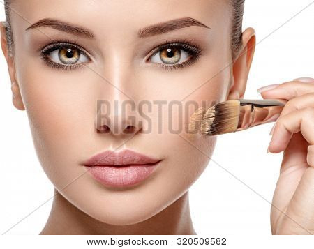 woman applying liquid tonal foundation  on the face . Closeup photo of cheek