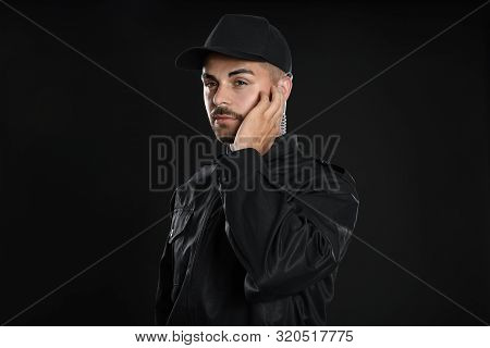 Male Security Guard In Uniform Using Radio Earpiece On Dark Background