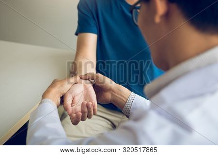 Physical Therapist Checks The Patient Wrist By Pressing The Wrist Bone In Clinic Room.