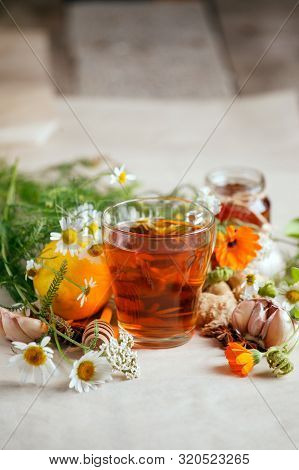 Cup Of Herbal Tea And Fresh Flowers, Lemin, Garlic, Ginger Root On Wooden Background - Seasonal Immu