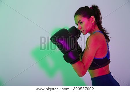 Picture of young gorgeous beautiful strong fitness woman boxer isolated with led flash lights make boxing exercises in gloves.