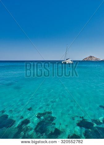 Modern Yacht Sailing In Turquoise Water Of Ocean In Bright Sunlight Against Clear Blue Sky