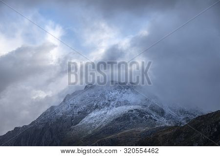Stunning Moody Dramatic Winter Landscape Image Of Snowcapped Tryfan Mountain In Snowdonia During Sto