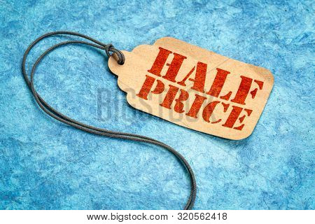 half price sign - a paper price tag with a twine against blue textured paper, shopping marketing concept