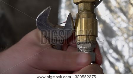 Plumber Unscrews A Wrench Unscrews A Nut On A Water Pipe