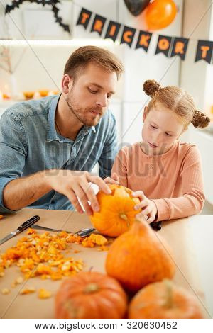 Young Father Helping His Little Daughter To Make Jack Olantern From Pumpkin For Halloween While They
