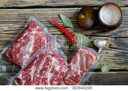 Cooking Meat In Vaccume Packaging. Meat With Spices On Wooden Background.