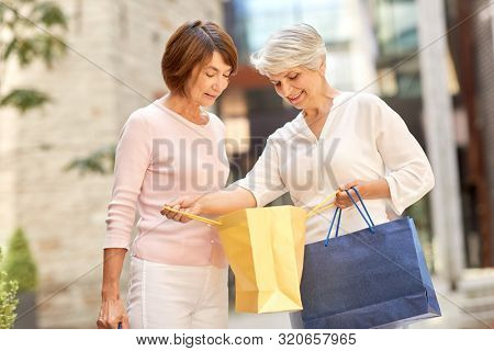 sale, consumerism and people concept - two senior women or friends with shopping bags on tallinn city street
