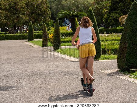 Lisbon, Portugal - 10 August 2019: Mother And Child Riding A Circ Electric Scooter Without Helmet By