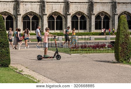 Lisbon, Portugal - 10 August 2019: Young Boy Riding A Circ Electric Scooter Without Helmet By The Mo