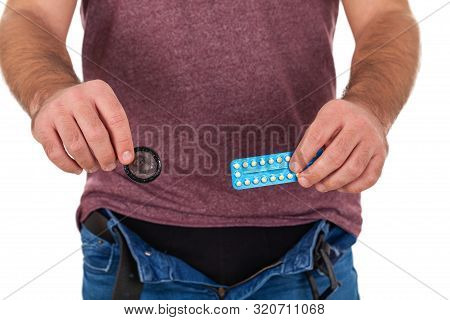 Close Up Picture Of Man Holding Birth Control Pills And Condom - Contraceptive Methods Concept